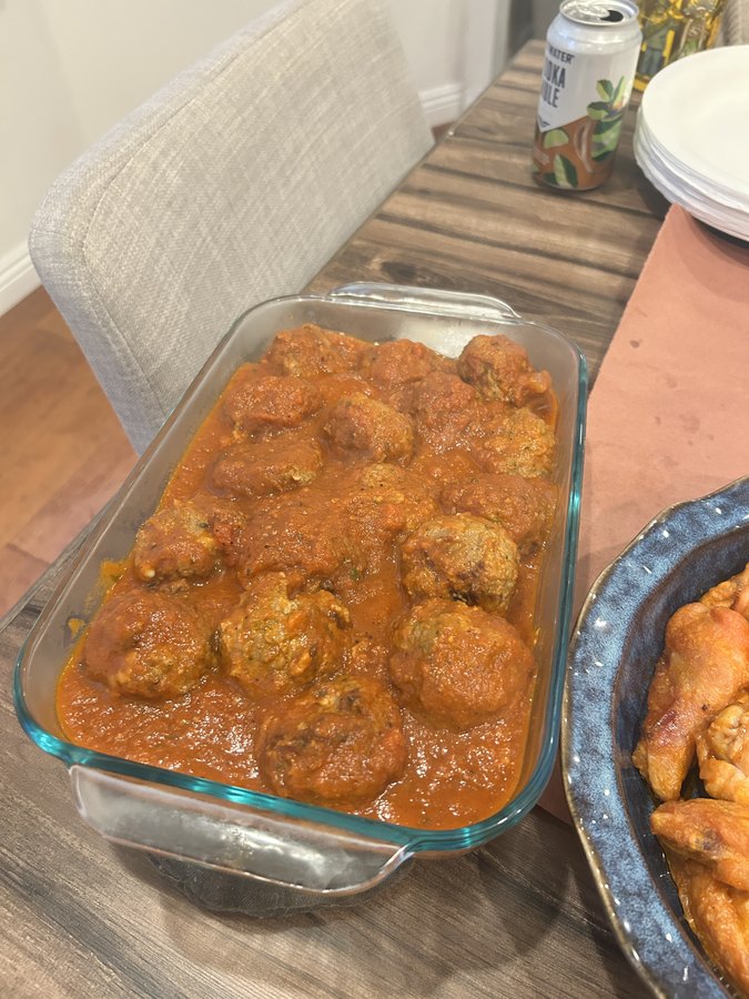 A baking dish of meatballs simmering in tomato sauce